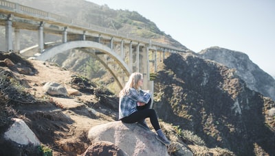 女人穿着格子衬衫坐在岩石上
